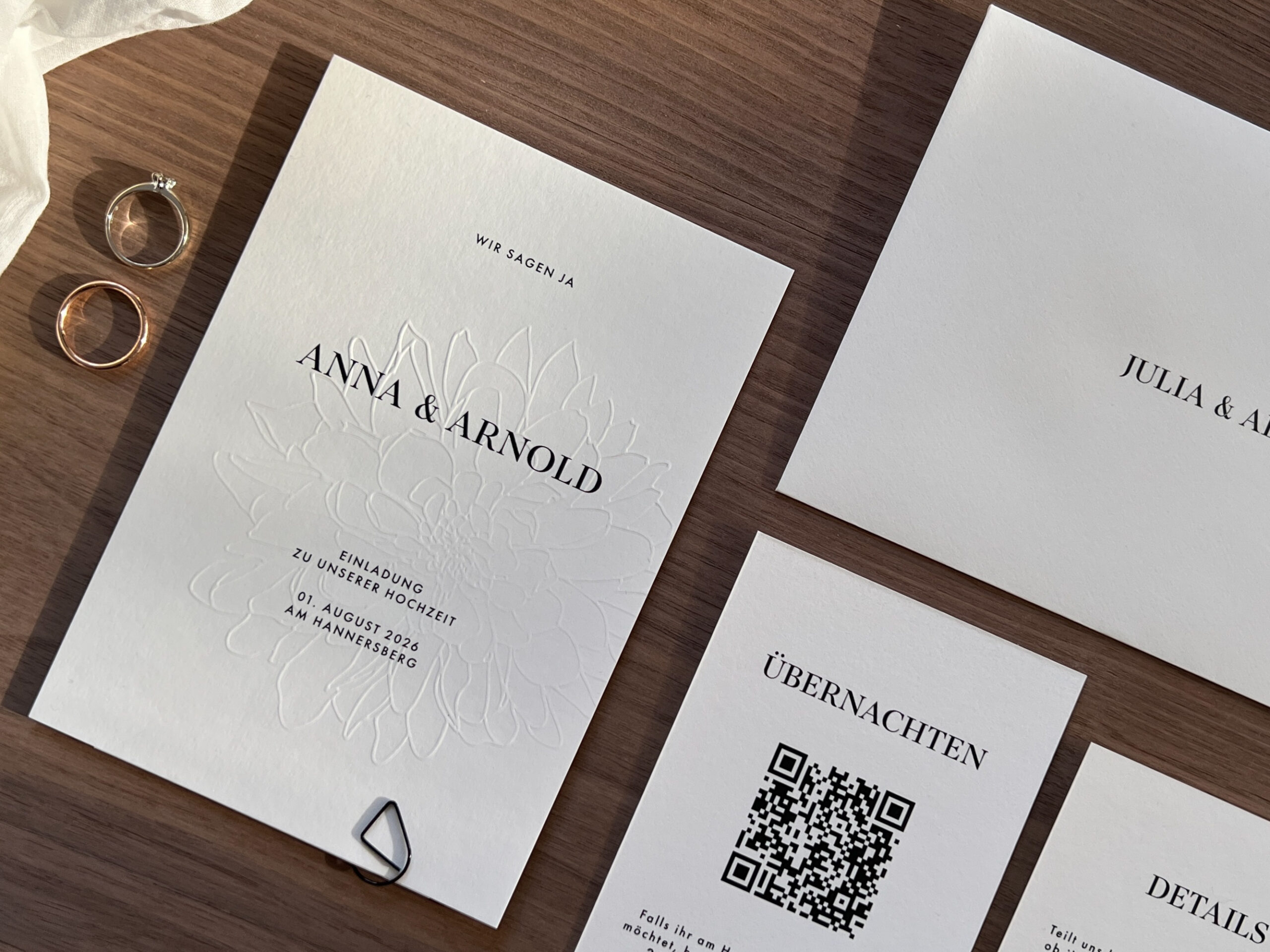 Hochzeitseinladungen und Ringe auf einem Tisch